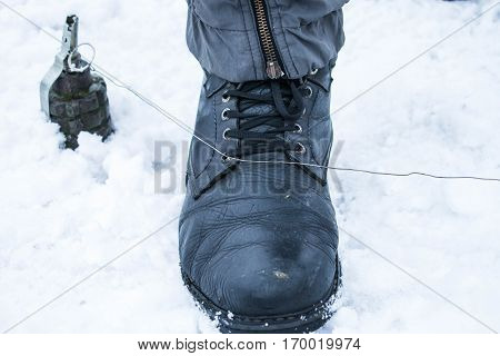 Big black shoes stepping on antipersonnel land mine