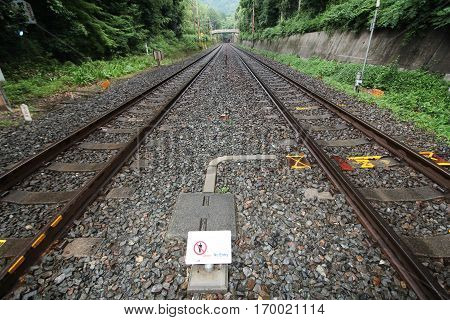 Warning signs can't be in the railway as No entry . Between the road crossing the tracks in the Arashiyama green areas of tourist attractions at JR Sagano line in rainy day.