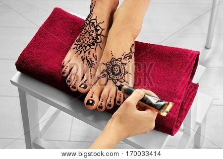 Woman applying henna on female foot