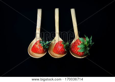strawberry in wooden spoon on black background isolated