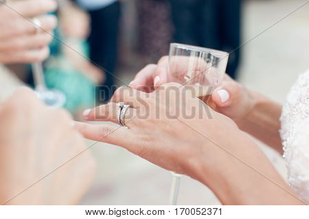Bride with wedding ring holds a glass of champagne close-up