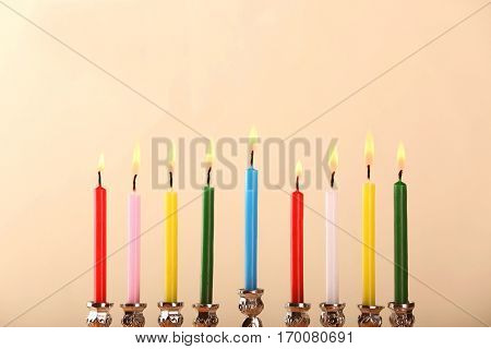 Menorah with colorful candles for Hanukkah on light background, close up