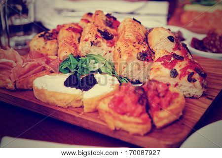Italian appetizers on wooden plank, close-up, toned image