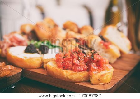 Italian appetizers on wooden plank, close-up