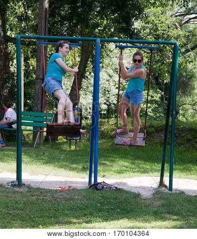 Russia, Arkhipo-Osipovka, June 20, 2016: adult girl riding on a swing in children's park.