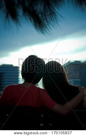 Happy sweethearts sit together  see the sunset
