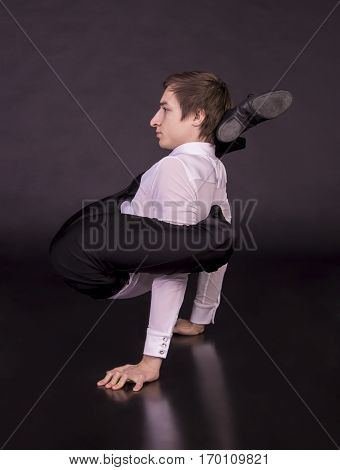 Extraordinary gymnast on a black background. The man with no bones. Studio photography of circus performers..