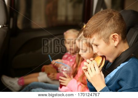 Cute children eating in a car