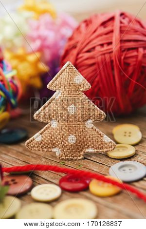 closeup of some cozy handmade christmas ornaments such as a fabric christmas tree and some christmas balls made with notions on a rustic wooden surface
