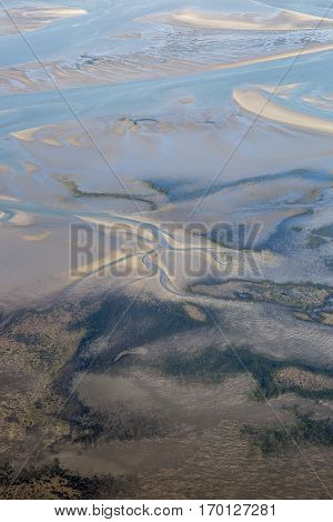 aerial view of the mudflat coastline at low tide with water winding in the mud and sand bank Frisian island Ameland The Netherlands