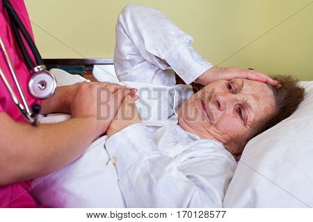 Picture of a bedridden old woman at home with her carer