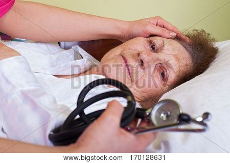 Picture of a bed ridden elderly woman with her care holding a stethoscope