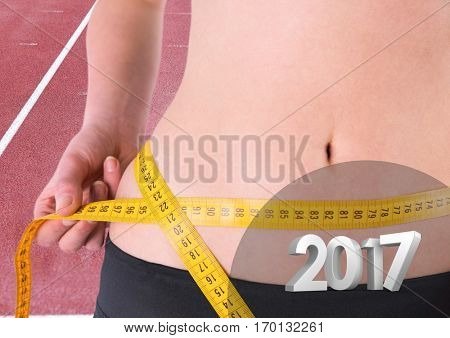 Mid section of woman measuring her waist against 3D 2017