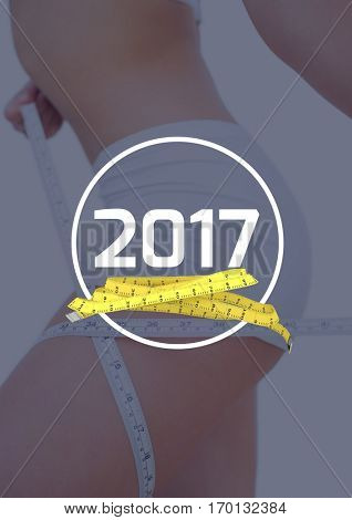 Mid section of woman measuring her thigh against 2017