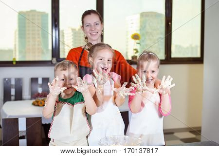 Three Lovely Children Together With Mother Preparing A Cake