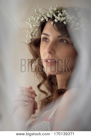 Portrait of sensual woman in circlet of flowers looking at camera