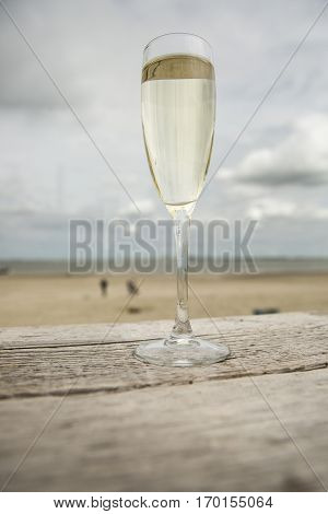 Champagne glass on a wooden table with beach background