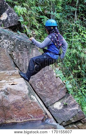 Beaufort,Sabah,Malaysia-Jan 28,2017:Muslim girl with scarf rappelling in Jempangah waterfall at Beaufort,Sabah,Borneo.Waterfall Abseiling activity adventure getting famous in Sabah,Borneo,Malaysia