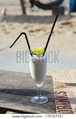 Cocktail glass with two straws and with beach landscape background