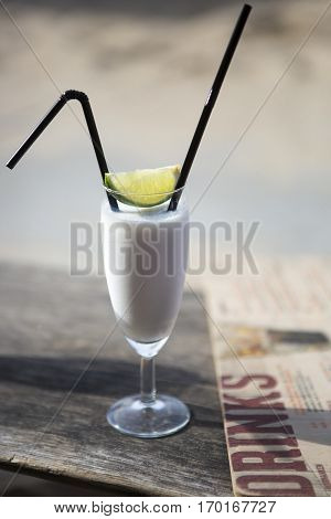 Cocktail glass with two straws and with beach landscape background