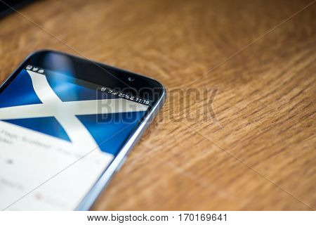 Smartphone On Wooden Background With 5G Network Sign 25 Per Cent Charge And Scotland Flag On The Scr