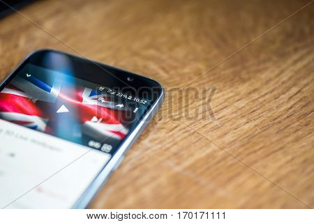 Smartphone On Wooden Background With 5G Network Sign 25 Per Cent Charge And Uk Flag On The Screen