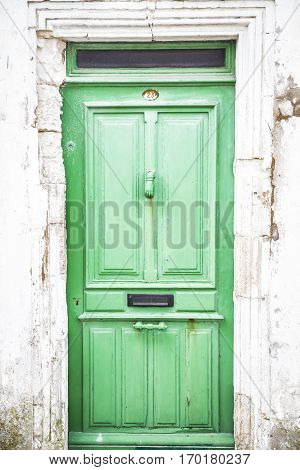 close up on a rustic old light green wooden door