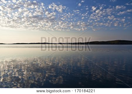 Norwegian landscape in the midnight sun with reflection of the clouds on still water