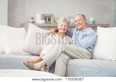 Portrait of romantic senior couple sitting on sofa in living room at home
