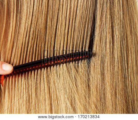 Photo of combing woman with long blond hair