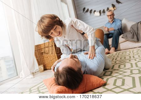 I love my son. Cheerful pleasant delighted men holding his song and having fun with him while lying on the floor