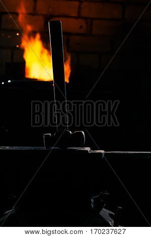 Blacksmith hammer on the anvil against the background of fire