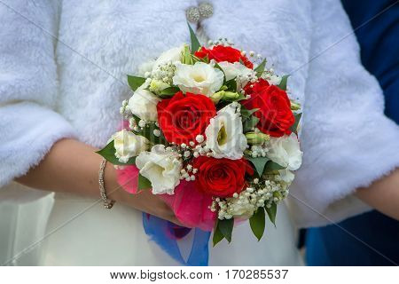 Beautiful wedding bouquet of red white flowers held by the bride