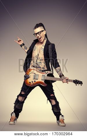 Excited rock musician is playing electrical guitar. Full length studio shot. Entertainment and musical concept. 