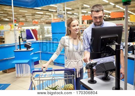 shopping, sale, consumerism and people concept - happy couple buying food and entering pin code at grocery store or supermarket self-service cash register