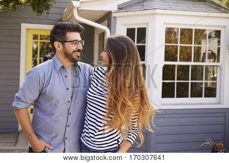 Portrait Of Excited Couple Standing Outside New Home