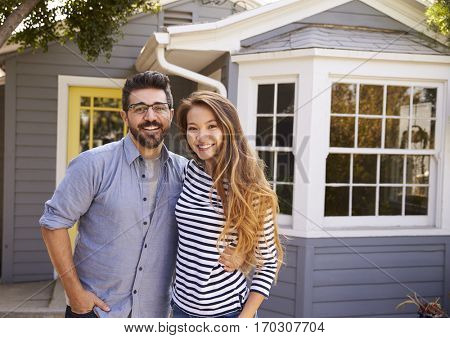 Portrait Of Excited Couple Standing Outside New Home