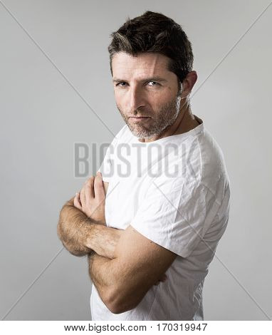 close up portrait of young attractive man with blue eyes looking angry and mad in rage emotion and upset facial expression isolated on grey background posing with folded arms