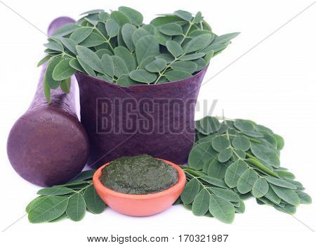 Edible moringa leaves in a vintage mortar with ground paste