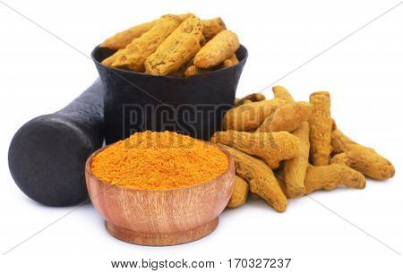 Whole and ground turmeric with mortar and pestle over white background