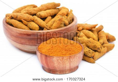 Whole and ground turmeric in bowl over white background