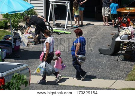 JOLIET, ILLINOIS / UNITED STATES - JUNE 17, 2016: People shop at a garage sale in the Wesmere Estates neighborhood of the Wesmere Country Club in Joliet.