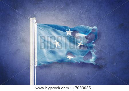 Torn flag Federated States of Micronesia flying against grunge background.