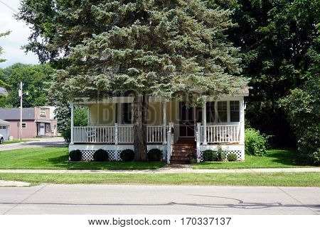 HARBOR SPRINGS, MICHIGAN / UNITED STATES - AUGUST 4, 2016: A Victorian home behind a blue spruce tree (Picea pungens) in Harbor Springs, Michigan.