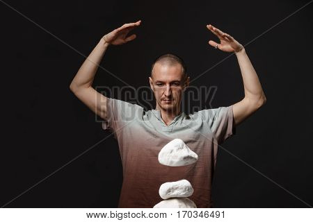 Telekinesis concept  - man making stones levitating with power of thought, dark studio background