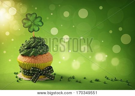 Cupcake with clover cakepick on a wooden background