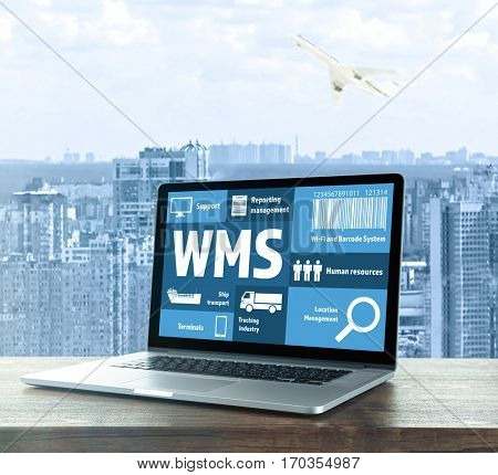 Warehouse management system concept. Laptop on table against cityscape background