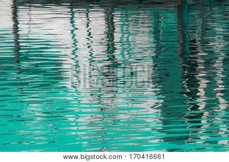 Reflection of  a pier in the waters of lake created by the light of the setting sun forming different size and shape of glimmer and colors.