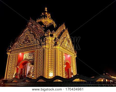 Golden temple of gods is lighted by spotlights in the night of Thailand.