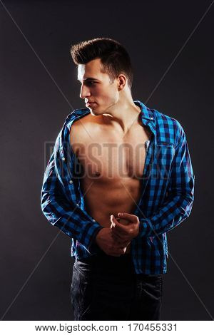 Sexy young man in a shirt with a naked torso on a dark background